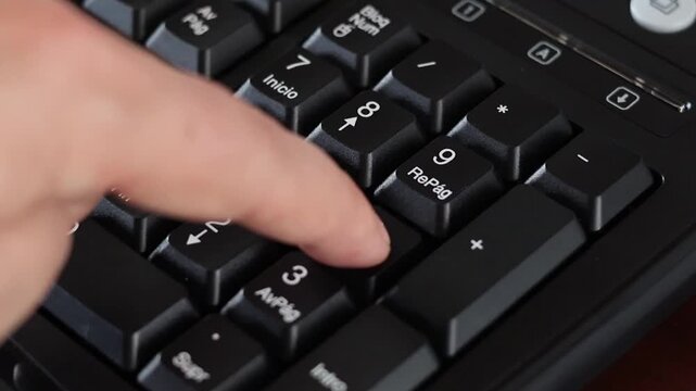 Un primer plano de un teclado con n&uacute;meros con el dedo de una mujer adulta marcando los n&uacute;meros con algo de desenfoque