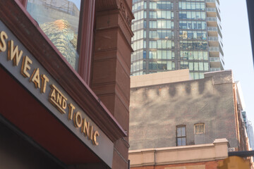 Naklejka premium defocused sign of Sweat and Tonic, a fitness center, located at 225 Yonge St, The Ryrie Building, Toronto (contrast of architecture styles)