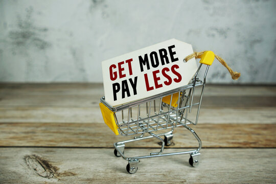 Get More Pay Less text on price tag and trolley shopping cart on wooden background