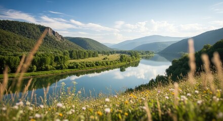 A serene river flowing through a lush green valley with mountains in the background.