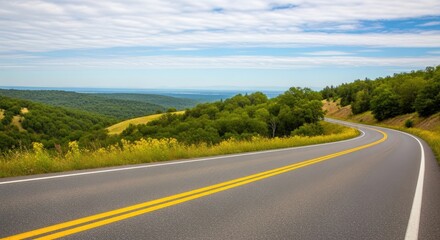 Fototapeta premium A winding road with yellow stripes and green trees on the side, leading to a distant horizon.
