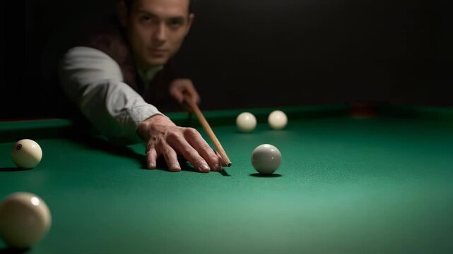 Focused man playing billiards aiming cue ball on green billiard table