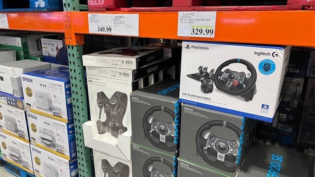 Logitech G923 racing wheel and accessories displayed on shelves at Costco shopping warehouse, showcasing gaming gear and electronics for enthusiasts