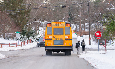 yellow school bus stopping on residential street after snow