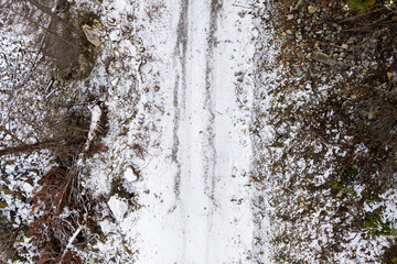 Fototapeta premium Snowy Dirt Road With Tire Tracks and Rocky Terrain in British Columbia, Canada