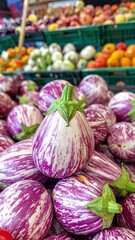 Fototapeta premium Fresh, striped eggplants stacked at a farmers market, other produce blurred in background