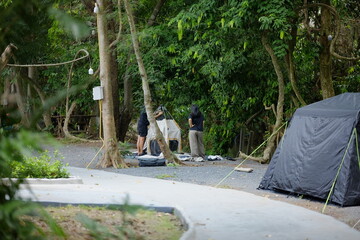 People Setting Up Tents in a Wooded Forest Campsite Area