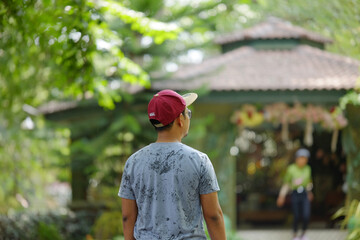 Man in Red Cap Walking in Green Park, Back View, Summer Leisure