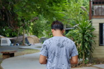 Man Walking Away from Camera Towards a Forest Campsite