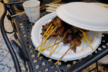 Delicious freshly grilled satay skewers served on a disposable plate