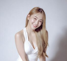 A beautiful young woman with simple hair looks directly at the camera in a bright background portrait showing strength individuality and modern femininity.