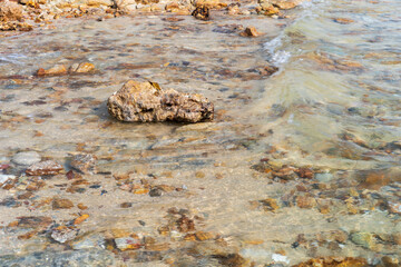 closeup sea sand beach with rocks stones on coast or island with nature little waves for summer holiday travel and daylight seascape landscape background at Sai Kaew Beach in Thailand and wave motion