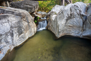 summer waterfall stream and rocks stones on nature clear flow motion water and pond in jungle or fresh natural forest at Phalad Waterfall in Lan sang national park Thailand for landscape background
