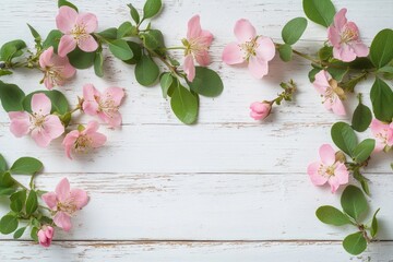 Delicate pink flowers with green leaves arranged on rustic white wooden surface creating a soft and natural frame