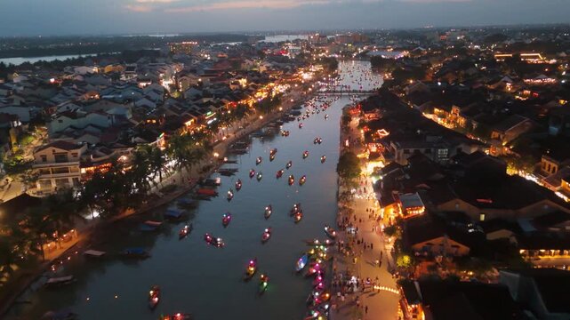 Magical aerial view of Hoi An Ancient Town, Vietnam, at dusk. Traditional colorful lanterns illuminate the Thu Bon River and historic houses, highlighting the UNESCO World Heritage site and cultural t