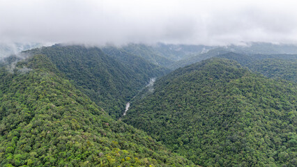Fototapeta premium Breathtaking aerial view of the lush green mountains in Agua Clara, Valle del Cauca, Colombia, enveloped in mist.