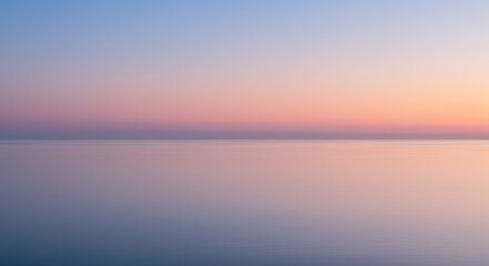 Obraz premium A serene, soft-focus view of a calm body of water at sunrise or sunset. Blending of pastel colors across the horizon