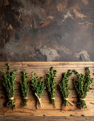 A flat lay photograph features several bundles of fresh, green sprigs of a flavorful herb tied with twine on wood. Background has a dark texture
