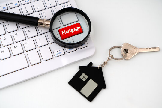 A Red keyboard key labeled 'Mortgage" under magnifying glass alongside a house key with a miniature house keychain