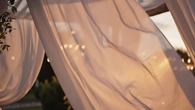 Elegant outdoor wedding reception decor with white curtains and floral arrangements