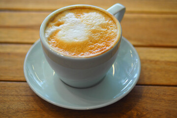 Warm drink in a white cup on a wooden table