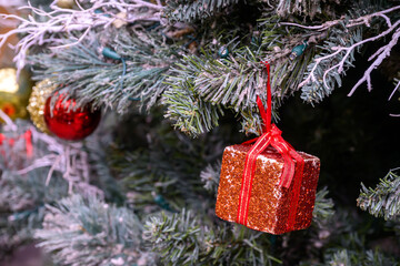 Close-up of a beautifully decorated ornament hanging on a artificial Christmas tree.