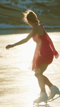 A graceful figure skater glides effortlessly across a shimmering ice surface, dressed elegantly in a bright red dress, capturing the enchanting beauty of winter sports in a scenic outdoor environment.