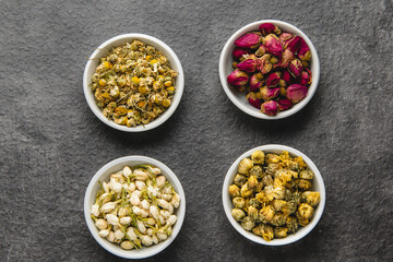 Assortment of Dried Herbs and Spices in White Bowls on Dark Background.