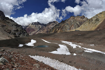 A small lake frozen in winter high in the mountains. The water of a small lake between the rocks in the snowy mountains is frozen