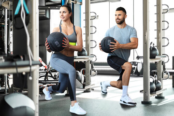 Beautiful young sports couple is working out with medicine ball in gym.