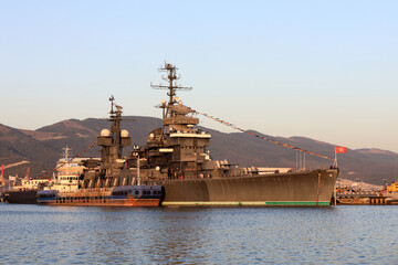 Fototapeta premium Large warship docked in port with mountains in background