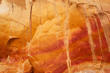 Close-up portrait of a multi-toned orange red sand dune wall featured on the sandy cliffs along the shores of Fraser Island, Queensland Australia.