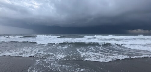 Fototapeta premium Stormy Beach Scene with Dark Clouds and Rolling Waves at Dusk