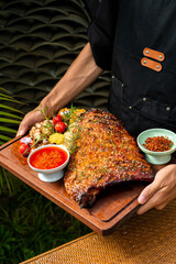 The chef was holding an iron baking tray in his hands, on which were roasted lamb chops and various seasonings.