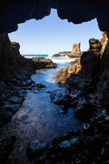 Looking out from the iconic cave at Cathedral Rocks located amongst the rocky coastline near Kiama on the South Coast of NSW, Australia. Captured with a long exposure on a clear sky on sunrise.