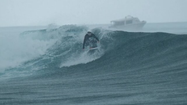 Surfer rides the wave in the ocean during rainy day