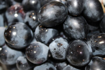 Fresh black grapes on display at a local market in the afternoon sunlight, ready for purchase