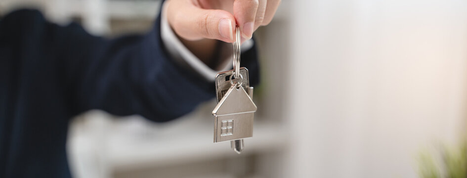 Close up view realtor broker holding home keychain in her hand and showing to new owner.