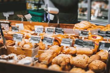 Fresh, delicious pastries - bread and sweet rolls in an assortment on wooden shelves in a modern European supermarket with its own bakery. High quality photo