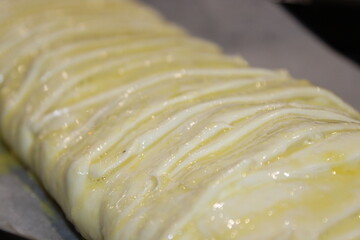 Bakery worker prepares dough on a baking tray with oil in a kitchen during evening hours