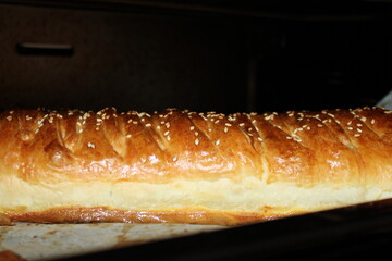 Fresh bread with sesame seeds baking in an oven during the morning preparation for the day