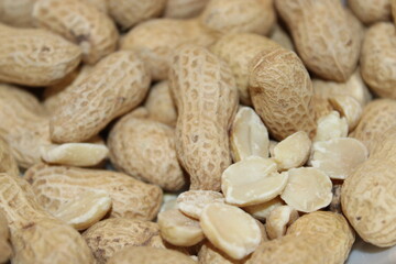 Peanuts in shell and shelled on a surface in a close-up view during daylight hours