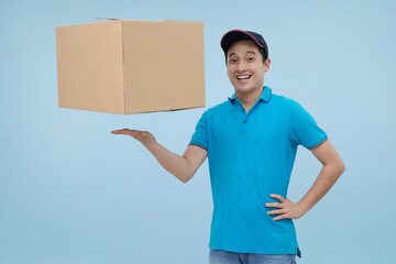 Happy young Asian male courier smiling confidently while presenting or holding a single large cardboard delivery box, symbolizing easy, reliable service and successful completion of the task