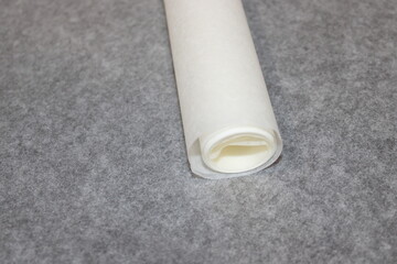 Roll of parchment paper on gray craft table during baking preparation