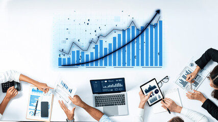 A professional business team engages in detailed analysis of financial data and charts during a strategic meeting in a modern office setting. Axiom