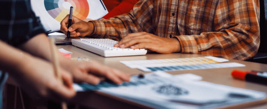 A team of creative professionals focuses on a design project in a modern office. Color palettes and sketches are visible, highlighting a collaborative and innovative atmosphere. SACTR