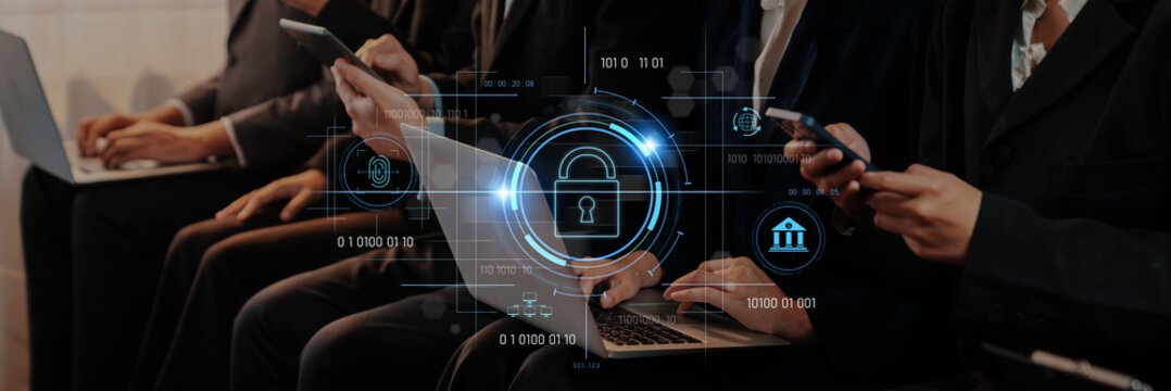 A group of professionals using digital devices in a modern office setting. A lock icon symbolizes the importance of cybersecurity and data protection in today business environment. Trope - Powered by Adobe