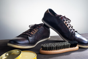 men's shoes with care accessories on wooden table.