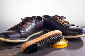 Leather shoes and shoe polish equipment on a wooden table.