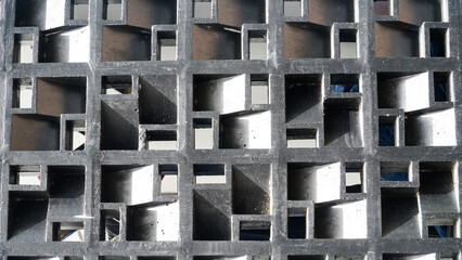 Modern architectural texture formed by a repeating grid of geometric shapes and openings, creating a captivating play of light and shadow on a building's exterior